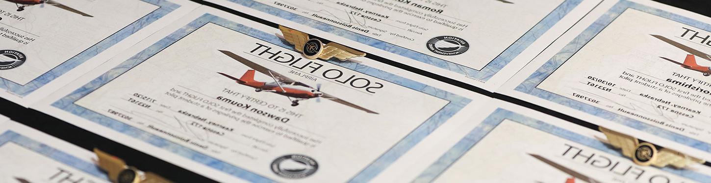 Solo Flight Certificates and wings sit on a table during a ceremony